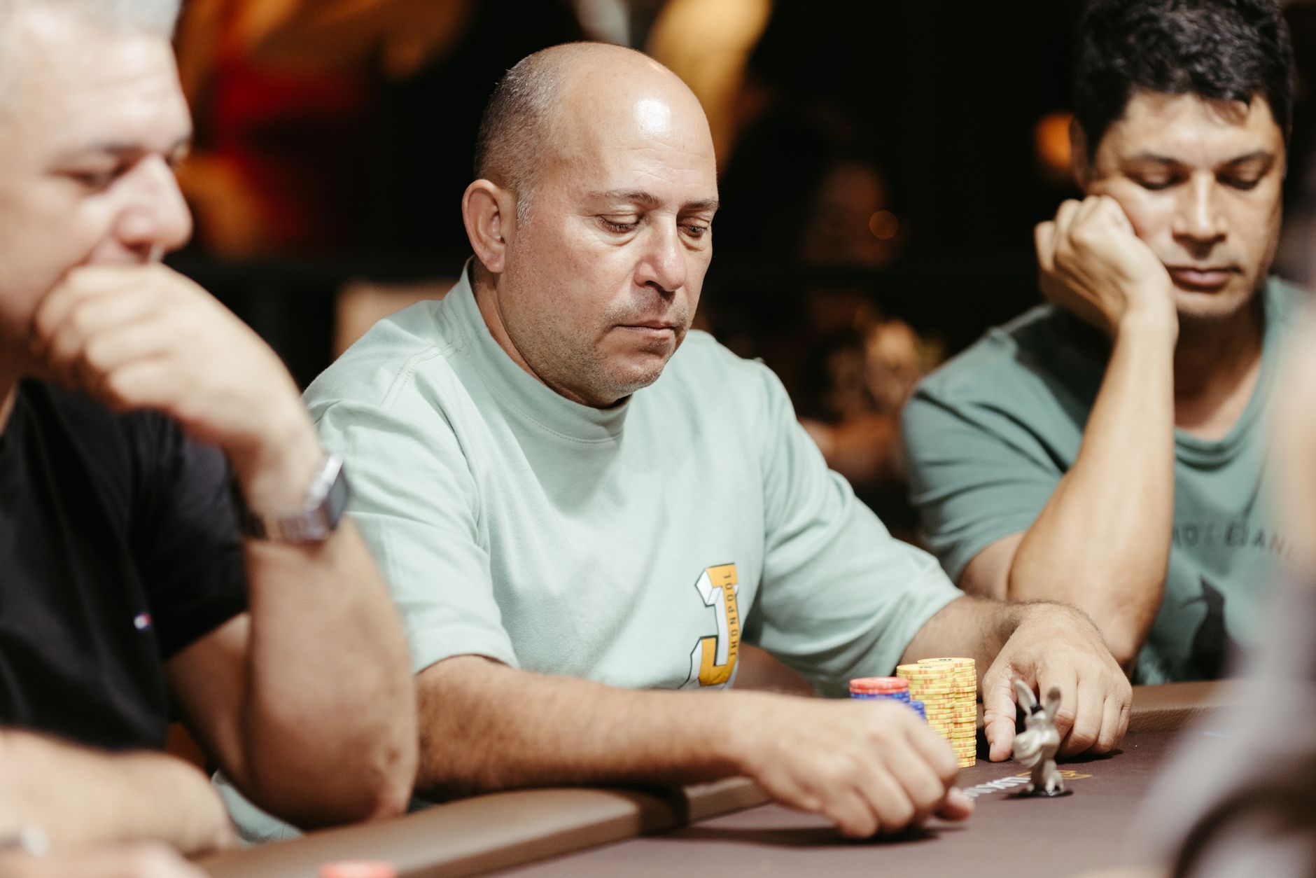 Groupe d'hommes adultes concentrés sur une partie de poker à une table de casino.