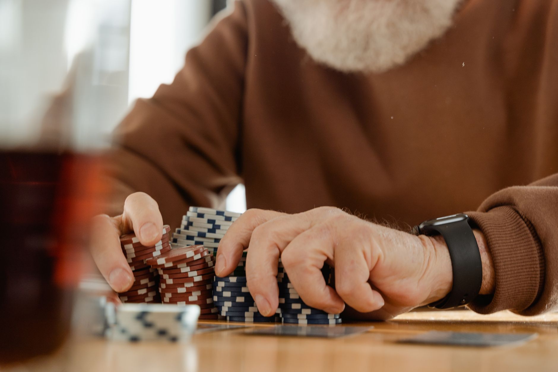 Personne âgée concentrée sur une partie de poker avec des jetons à une table à l'intérieur. Capturé avec une ambiance chaleureuse et vintage.